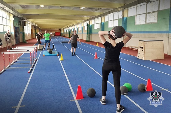 Na zdjęciu uczestnicy zajęć ćwiczą na hali sportowej.