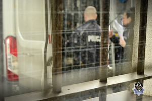 Na zdjęciu policjanci zamykają drzwi radiowozu.