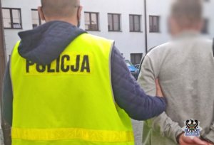 Na zdjęciu policjant prowadzi zatrzymanego mężczyznę.