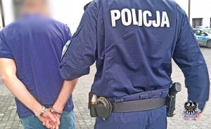 Na zdjęciu policjant prowadzi zatrzymanego mężczyznę.