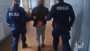 Na zdjęciu policjanci prowadzą jednego z zatrzymanych mężczyzn.
