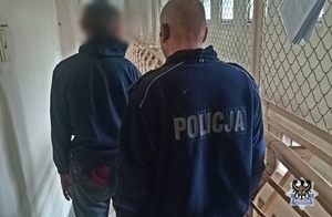 Na zdjęciu policjant prowadzi zatrzymanego do celi.