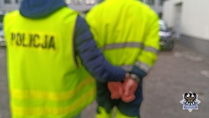 Na zdjęciu policjant prowadzi zatrzymanego mężczyznę.