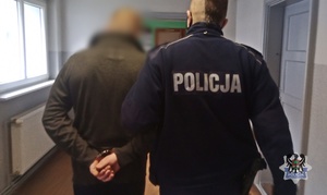 Na zdjęciu policjant prowadzi pierwszego z zatrzymanych mężczyzn.