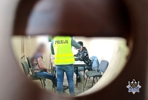 Na zdjęciu policjanci wykonują czynności z zatrzymaną kobietą - inne ujęcie.