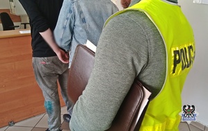 Na zdjęciu policjant zakłada kajdanki zatrzymanemu mężczyźnie.
