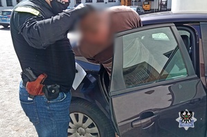 Na zdjęciu policjant umieszcza zatrzymanego mężczyznę w radiowozie.