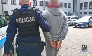 Na zdjęciu policjant prowadzi drugiego z zatrzymanych mężczyzn.