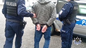 Na zdjęciu policjanci prowadzą jednego z zatrzymanych mężczyzn do radiowozu.
