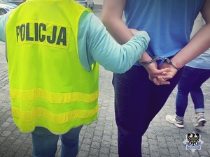 Na zdjęciu policjantka prowadzi zatrzymanego mężczyznę.