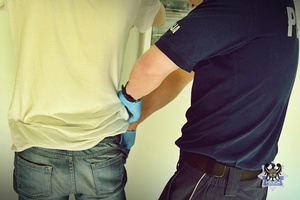 Na zdjęciu policjant sprawdza zatrzymanego mężczyznę.