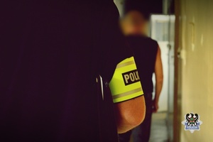 Na zdjęciu policjant prowadzi zatrzymanego mężczyznę