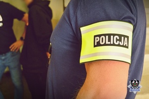 Na zdjęciu policjanci pilnują jednego z zatrzymanych mężczyzn.