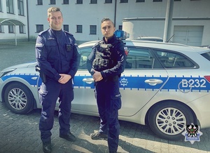 Na zdjęciu dwóch policjantów na tle radiowozu.