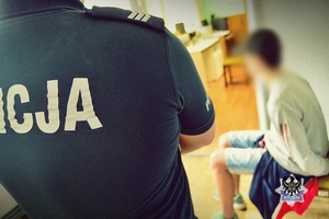Na zdjęciu policjant pilnuje zatrzymanego mężczyzny.