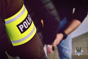 Na zdjęciu policjant zakłada kajdanki zatrzymanemu mężczyźnie.