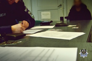 Na zdjęciu policjanci wykonują czynności procesowe z zatrzymanym mężczyzną.