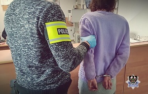 Na zdjęciu policjant pilnuje zatrzymanej kobiety.