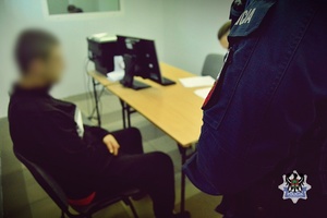 Na zdjęciu policjanci wykonują czynności procesowe z zatrzymanym mężczyzną.