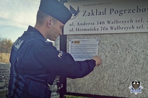 Na zdjęciu policjant umieszcza ulotkę dotyczącą bezpieczeństwa podczas akcji Znicz 2022.