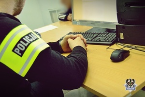 Na zdjęciu policjant wykonuje czynności procesowe z zatrzymanym mężczyzną.