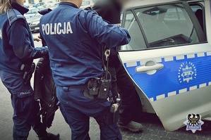Na zdjęciu policjanci prowadzą zatrzymanego mężczyznę.