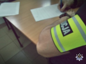 Na zdjęciu policjant sporządza dokumentację służbową.