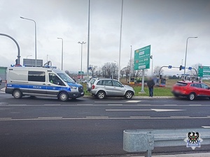 Na zdjęciu radiowóz oraz samochody biorące udział w zdarzeniu drogowy.