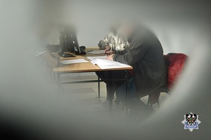 Na zdjęciu policjanci przesłuchują zatrzymanego mężczyznę.