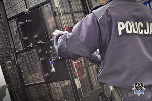Na zdjęciu policjant zamyka drzwi radiowozu.