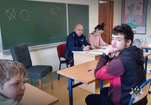 Na zdjęciu policjant oraz uczestnicy testu teoretycznego.
