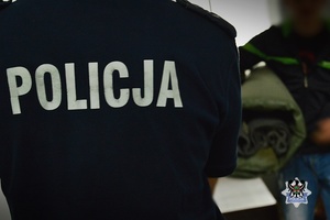 Na zdjęciu policjant zakłada kajdanki zatrzymanemu mężczyźnie.