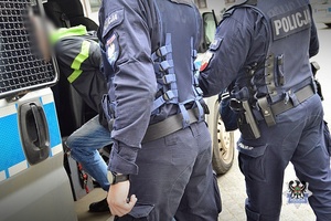 Na zdjęciu policjant zakłada kajdanki zatrzymanemu mężczyźnie.