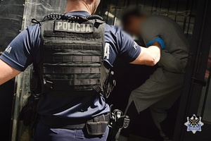 Na zdjęciu policjant umieszcza zatrzymanego w radiowozie .