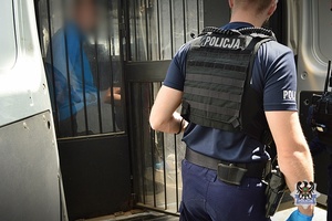 Na zdjęciu policjant umieszcza zatrzymanego w radiowozie.