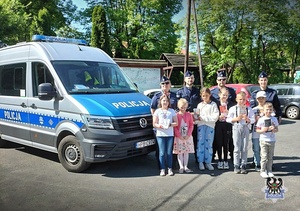 Na zdjęciu dzieci i policjanci przy radiowozie.