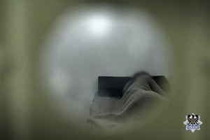 Na zdjęciu zatrzymany mężczyzna śpi w celi.