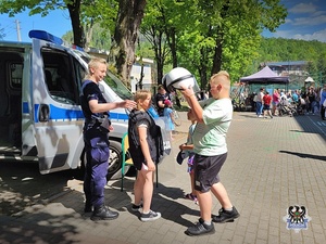 Na zdjęciu policjantka oraz dzieci biorące udział w festynie.