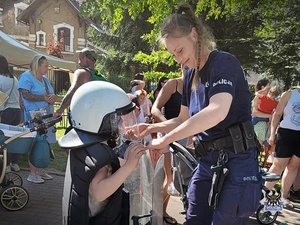 Na zdjęciu policjantka oraz dzieci biorące udział w festynie.
