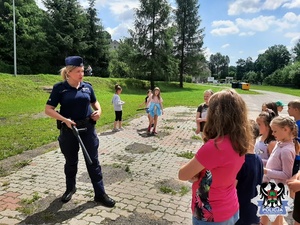 policjanta prezentuje dzieciom pałkę służbową