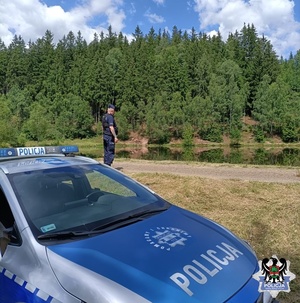 radiowóz i policjant przy zbiorniku wodnym