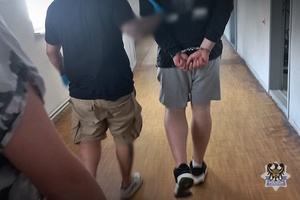 Na zdjęciu policjant prowadzi zatrzymanego meżczyznę.