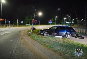 Na zdjęciu uszkodzony w wyniku kolizji drogowej samochód osobowy oraz latarnia uliczna.