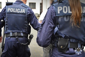 Na zdjęciu policjanci prowadzą zatrzymanego mężczyznę.