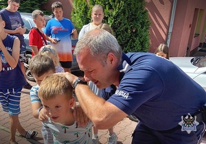 Na zdjęciu policjanci pokazują dzieciom chwyty transportowe używane przez policjantów w służbie.