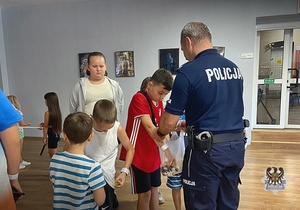 Na zdjęciu policjanci prowadzą pogadankę z dziećmi.