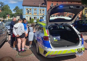 Na zdjęciu policjanci pokazują dzieciom samochód służbowy.