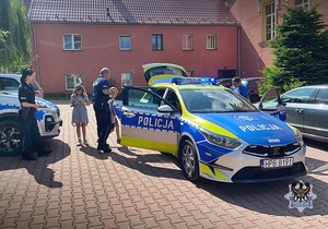 Na zdjęciu policjanci pokazują dzieciom samochód służbowy.