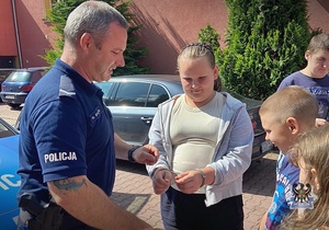 Na zdjęciu policjanci pokazują dzieciom chwyty transportowe używane przez policjantów w służbie.