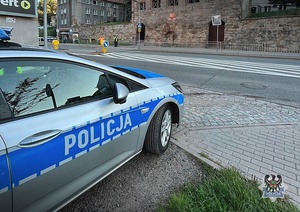 Na zdjęciu radiowóz oraz policjanci przy przejściu dla pieszych przy szkole podstawowej.